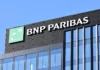 New Nature Transition Model for the Finance Sector BNP Paribas corporate office building with logo and large sign on a glass facade against a blue sky.