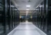 Creatio and Bayanat Expand AI Banking Automation in MENA Data center corridor flanked by glass-front server racks, leading to a control room with chairs and multiple screens at the far end.