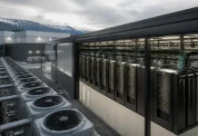 Blue Owl Leads $2.4 Billion AI Factory Financing for IREN Row of outdoor cooling units beside a data center server racks housed in a glass-enclosed enclosure, with mountains in the distance.