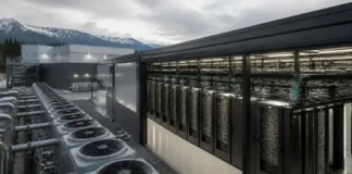 Blue Owl Leads $2.4 Billion AI Factory Financing for IREN Row of outdoor cooling units beside a data center server racks housed in a glass-enclosed enclosure, with mountains in the distance.
