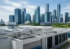 Singapore Commits S$220 Million to Boost Fintech Innovation Skyline of glass skyscrapers behind a white industrial building with exposed pipes on the roof.