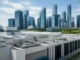 Singapore Commits S$220 Million to Boost Fintech Innovation Skyline of glass skyscrapers behind a white industrial building with exposed pipes on the roof.